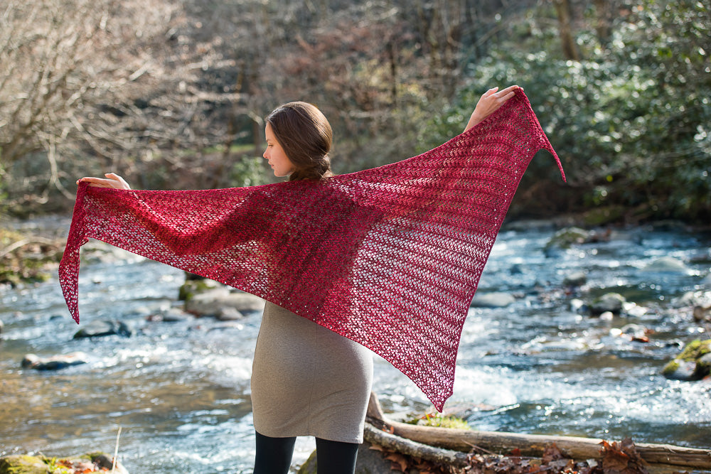 Woman holding out a large red lacy shawl.